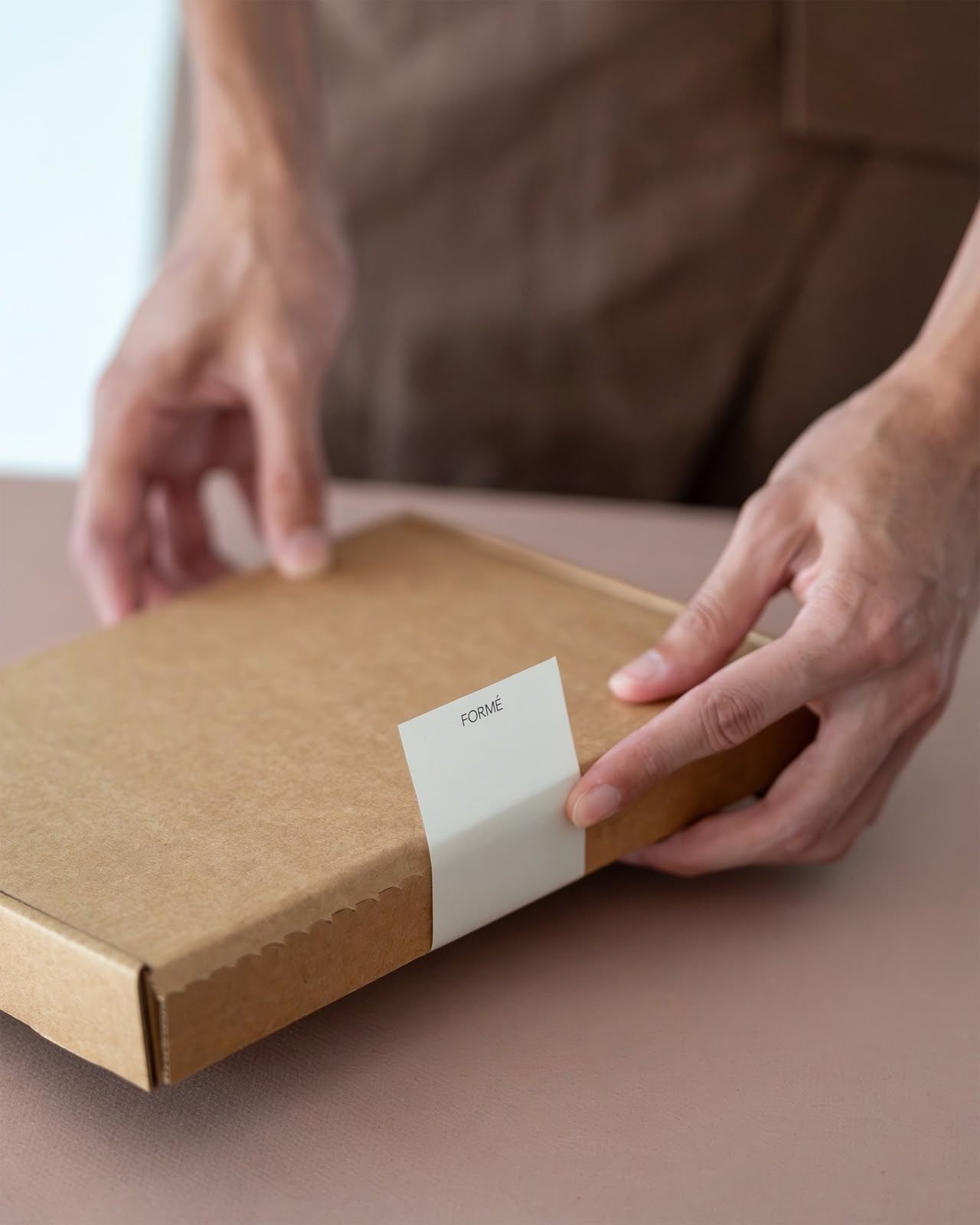 Hands closing a kraft box.